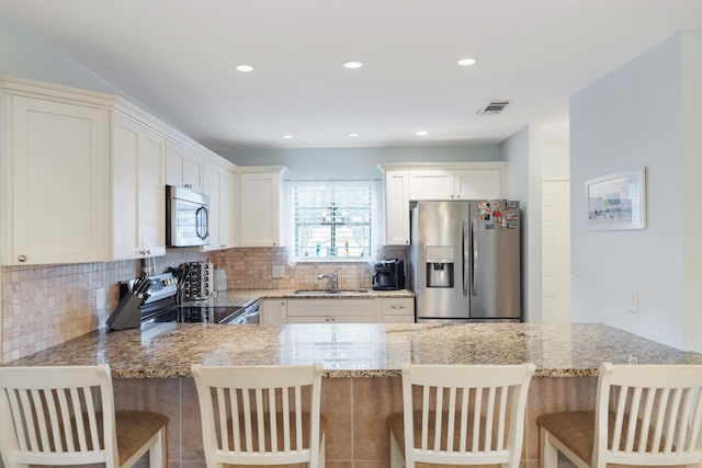 25 Misty Cv Unit 115, Miramar Beach, FL 32550 - kitchen featuring stainless steel appliances, a sink, backsplash, light stone counters, and a peninsula