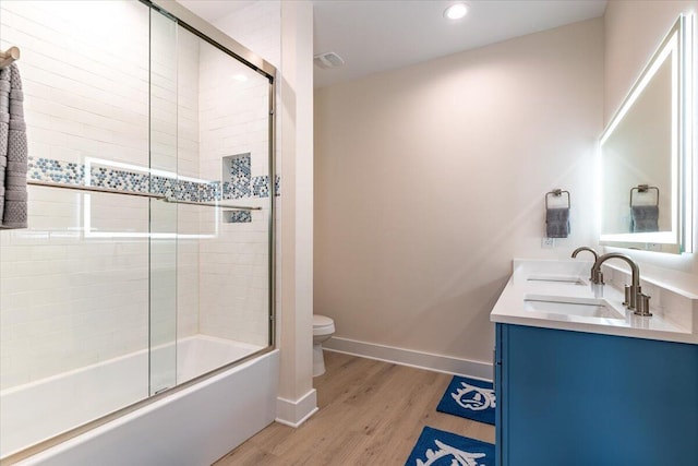 8169 White Sands Blvd, Navarre, FL 32566 - full bath featuring toilet, wood finished floors, bath / shower combo with glass door, baseboards, and double vanity