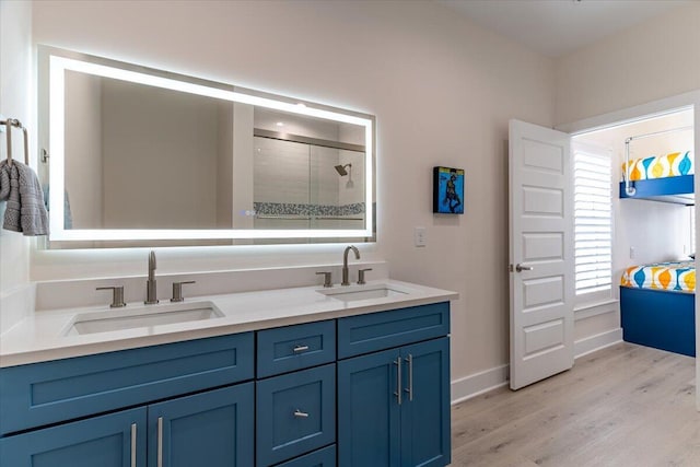 8169 White Sands Blvd, Navarre, FL 32566 - bathroom featuring double vanity, wood finished floors, baseboards, and tiled shower