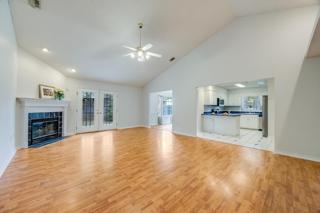 2803 Macgregor Ln, Crestview, FL 32539 - unfurnished living room with light wood-style floors, ceiling fan, high vaulted ceiling, baseboards, and a tile fireplace