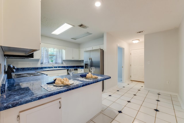 2803 Macgregor Ln, Crestview, FL 32539 - kitchen with stainless steel fridge, a sink, dark countertops, white cabinets, and baseboards