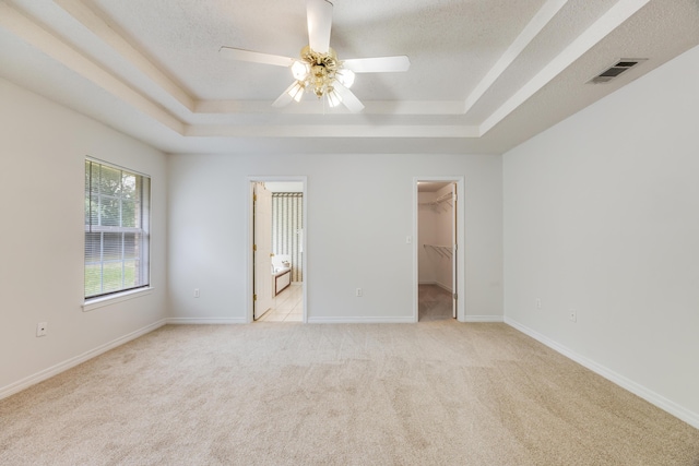 2803 Macgregor Ln, Crestview, FL 32539 - unfurnished bedroom featuring a tray ceiling, a walk in closet, light carpet, a textured ceiling, and ceiling fan