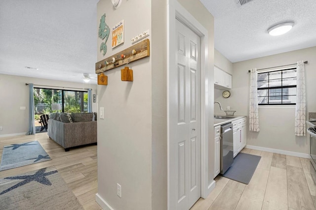 15 Cypress St Unit 268, Santa Rosa Beach, FL 32459 - kitchen featuring stainless steel dishwasher, a textured ceiling, light wood-style floors, white cabinets, and light countertops