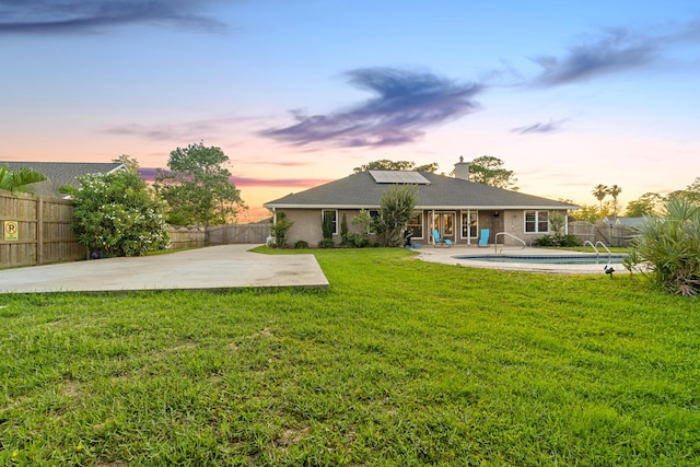 108 Colony Bay Harbour Dr, Panama City Beach, FL 32407 - back of house at dusk featuring a patio area, roof mounted solar panels, and a chimney