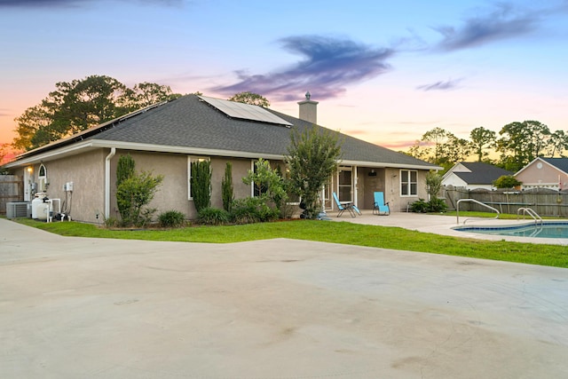 108 Colony Bay Harbour Dr, Panama City Beach, FL 32407 - view of front of house featuring roof mounted solar panels, stucco siding, a patio, a chimney, and central AC unit