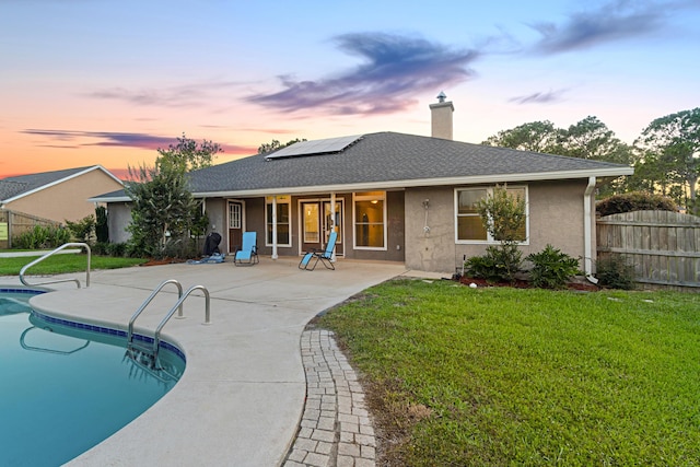 108 Colony Bay Harbour Dr, Panama City Beach, FL 32407 - rear view of property with roof mounted solar panels, a patio, a chimney, stucco siding, and a shingled roof