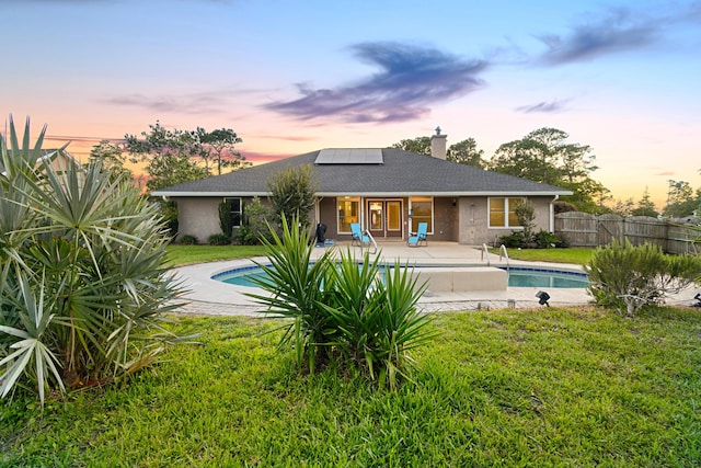 108 Colony Bay Harbour Dr, Panama City Beach, FL 32407 - back of property at dusk featuring solar panels, a patio area, a chimney, and a shingled roof