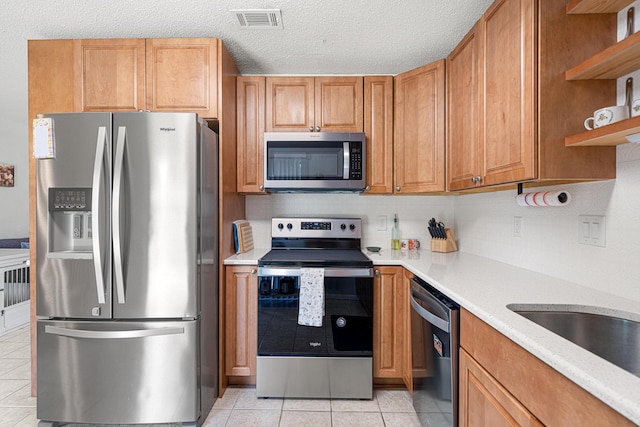 617 Schneider Dr, Fort Walton Beach, FL 32547 - kitchen with appliances with stainless steel finishes, light tile patterned flooring, open shelves, a textured ceiling, and brown cabinets