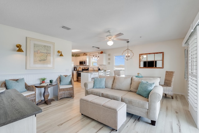 8436 Gulf Blvd Unit 734, Navarre, FL 32566 - living room with ceiling fan, light wood finished floors, a wainscoted wall, and a chandelier