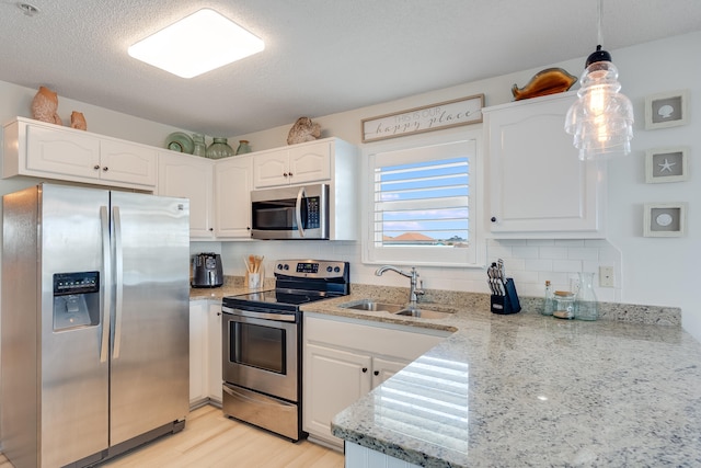 8436 Gulf Blvd Unit 734, Navarre, FL 32566 - kitchen with appliances with stainless steel finishes, a sink, white cabinetry, light stone countertops, and light wood-style flooring