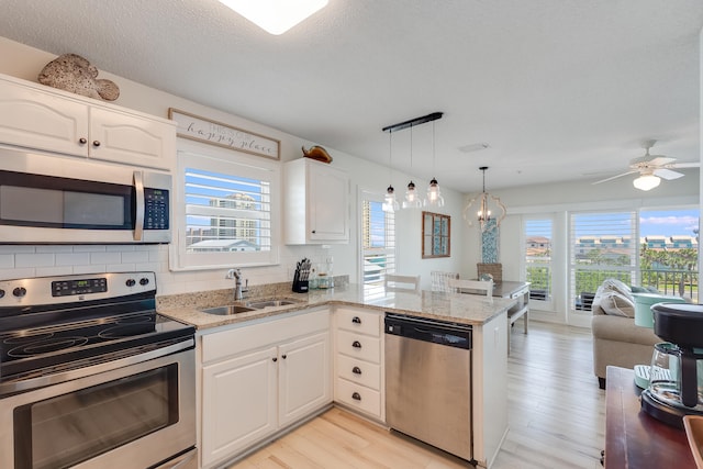 8436 Gulf Blvd Unit 734, Navarre, FL 32566 - kitchen featuring appliances with stainless steel finishes, a sink, plenty of natural light, a peninsula, and a textured ceiling