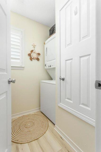 8436 Gulf Blvd Unit 734, Navarre, FL 32566 - washroom featuring stacked washer and clothes dryer, light wood-style flooring, and baseboards