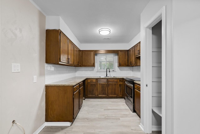 3437 Auburn Rd, Crestview, FL 32539 - kitchen with electric stove, a sink, tasteful backsplash, light wood-style floors, and brown cabinets