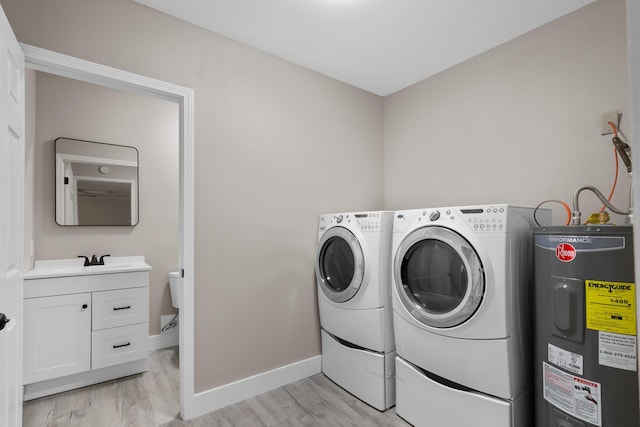 3437 Auburn Rd, Crestview, FL 32539 - washroom with water heater, washer and clothes dryer, light wood-style flooring, and baseboards