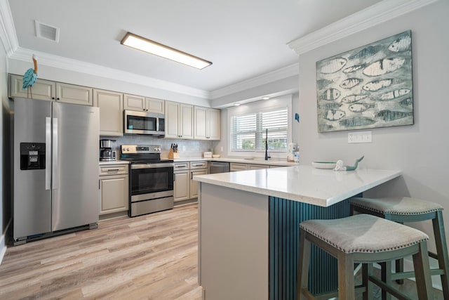 415 Gulf Shore Dr Unit 23, Destin, FL 32541 - kitchen with stainless steel appliances, a peninsula, crown molding, light wood-style flooring, and a kitchen bar