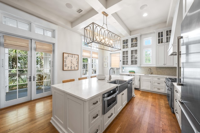 21 Founders Ct, Watersound, FL 32461 - kitchen featuring high quality appliances, beamed ceiling, french doors, a kitchen island with sink, and white cabinets