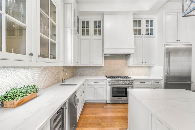 21 Founders Ct, Watersound, FL 32461 - kitchen with high quality appliances, custom exhaust hood, white cabinetry, and light stone countertops