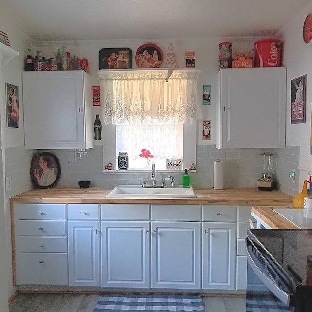 72 Park Ave, Defuniak Springs, FL 32435 - kitchen featuring a sink, backsplash, light countertops, and white cabinetry