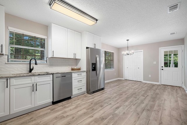 207 Oglesby Ave, Crestview, FL 32536 - kitchen with stainless steel appliances, a chandelier, light wood-type flooring, backsplash, and a textured ceiling