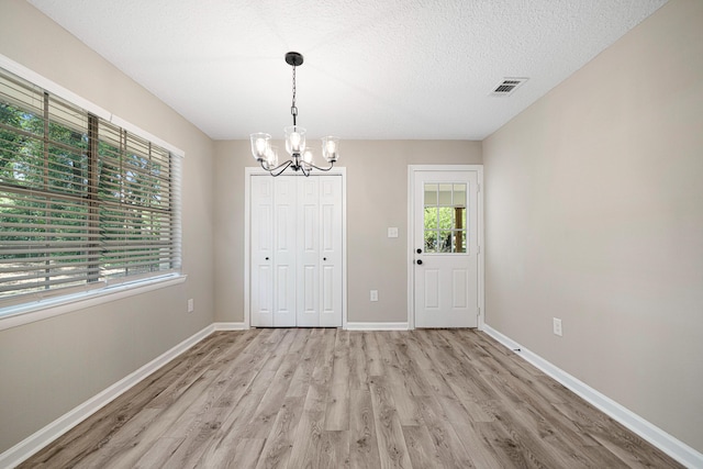 207 Oglesby Ave, Crestview, FL 32536 - unfurnished dining area featuring a chandelier, light wood finished floors, and a textured ceiling