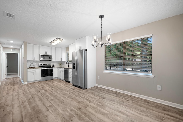 207 Oglesby Ave, Crestview, FL 32536 - kitchen featuring appliances with stainless steel finishes, light wood-type flooring, a chandelier, light countertops, and white cabinets