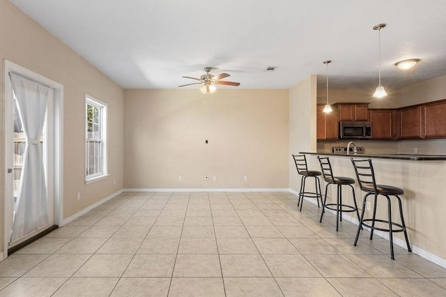 996 Leigh Ann Ln, Fort Walton Beach, FL 32547 - kitchen featuring stainless steel microwave, dark countertops, a kitchen bar, ceiling fan, and pendant lighting