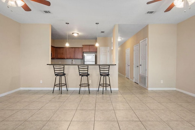 996 Leigh Ann Ln, Fort Walton Beach, FL 32547 - kitchen featuring ceiling fan, freestanding refrigerator, a breakfast bar, and light tile patterned floors