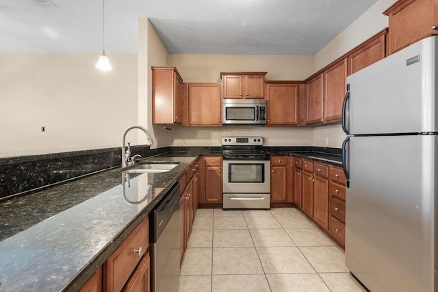 996 Leigh Ann Ln, Fort Walton Beach, FL 32547 - kitchen with stainless steel appliances, a sink, brown cabinets, light tile patterned flooring, and dark stone countertops