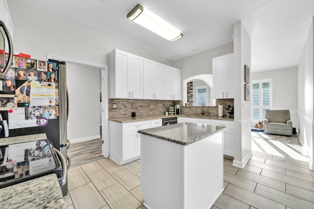 283 Stahlman Ave, Destin, FL 32541 - kitchen with arched walkways, electric range, tasteful backsplash, light stone countertops, and white cabinets
