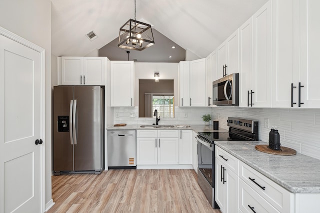 28 6th St, Shalimar, FL 32579 - kitchen featuring stainless steel appliances, a sink, white cabinets, vaulted ceiling, and light wood-style floors