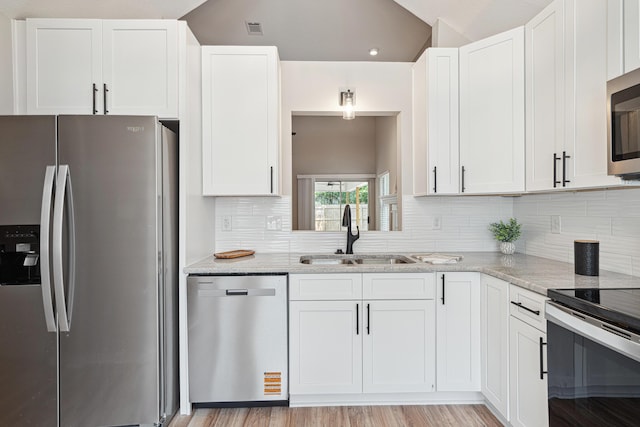 28 6th St, Shalimar, FL 32579 - kitchen with appliances with stainless steel finishes, a sink, backsplash, white cabinetry, and lofted ceiling