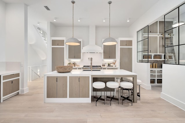 LOT36 Grande Pointe Cir, Inlet Beach, FL 32461 - kitchen featuring wall chimney exhaust hood, light wood-style flooring, light countertops, a spacious island, and pendant lighting