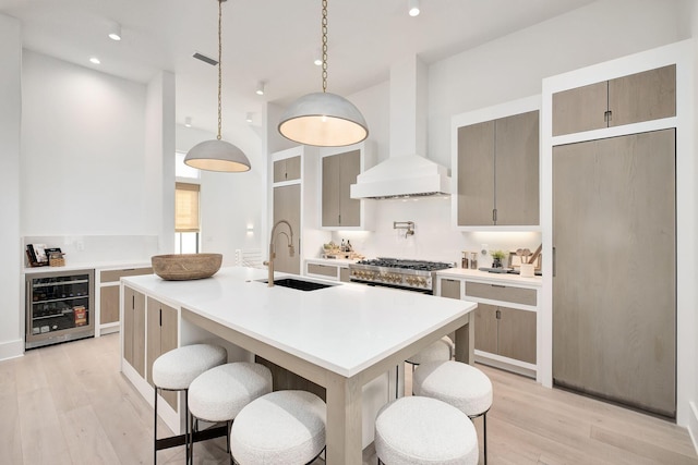 LOT36 Grande Pointe Cir, Inlet Beach, FL 32461 - kitchen featuring beverage cooler, a sink, wall chimney range hood, light wood finished floors, and a breakfast bar area