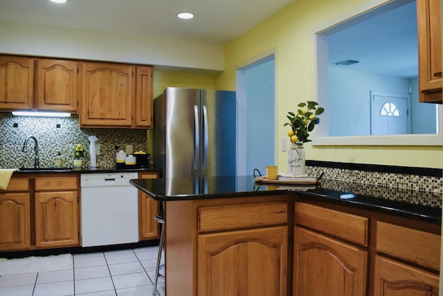 22 10th St, Shalimar, FL 32579 - kitchen with dishwasher, a sink, freestanding refrigerator, brown cabinets, and light tile patterned floors