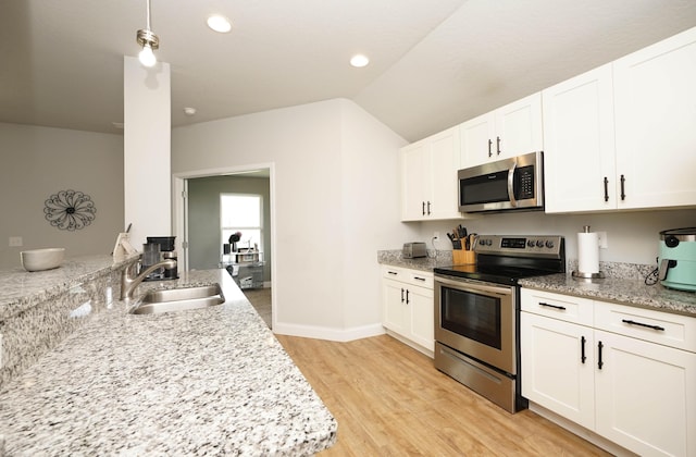 415 Scooter Cv, Crestview, FL 32539 - kitchen with stainless steel appliances, a sink, light wood-style flooring, white cabinetry, and vaulted ceiling