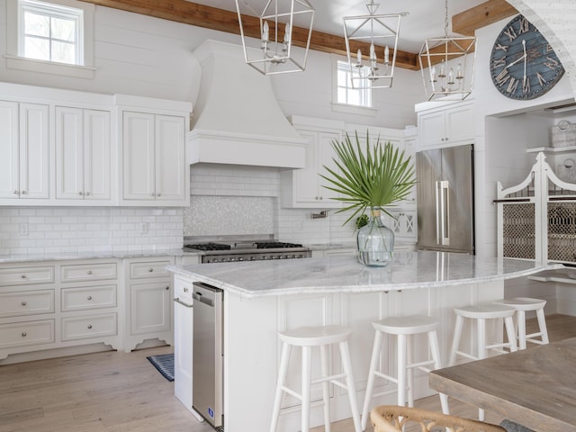 44 Tidepool Ln, Watersound, FL 32461 - kitchen featuring high end refrigerator, a kitchen island, backsplash, white cabinets, and light stone counters