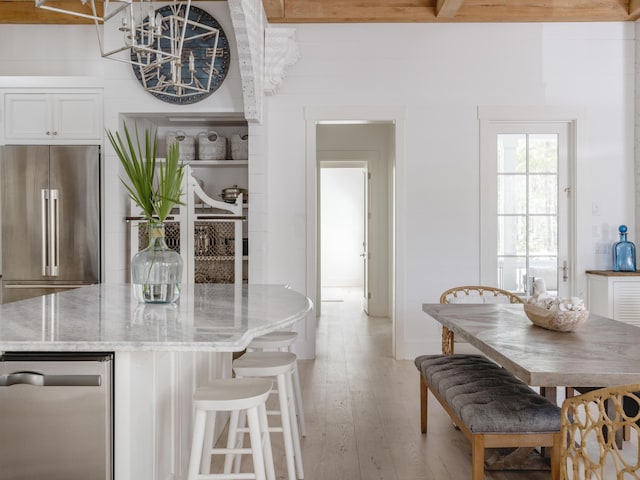 44 Tidepool Ln, Watersound, FL 32461 - kitchen with high quality fridge, light wood-style floors, light stone counters, white cabinetry, and a kitchen breakfast bar