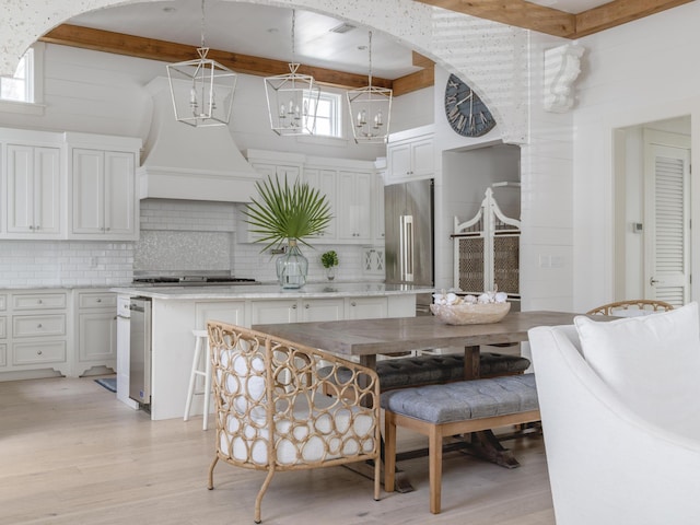 44 Tidepool Ln, Watersound, FL 32461 - dining space featuring a chandelier, light wood-style floors, beamed ceiling, arched walkways, and a towering ceiling