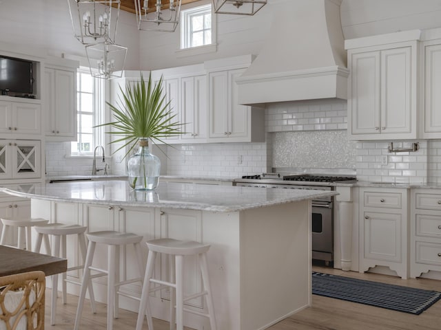 44 Tidepool Ln, Watersound, FL 32461 - kitchen with stainless steel range with gas cooktop, premium range hood, a center island, white cabinetry, and tasteful backsplash