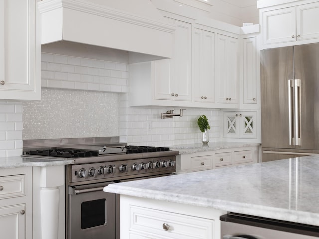 44 Tidepool Ln, Watersound, FL 32461 - kitchen with high end appliances, white cabinets, backsplash, light stone countertops, and premium range hood