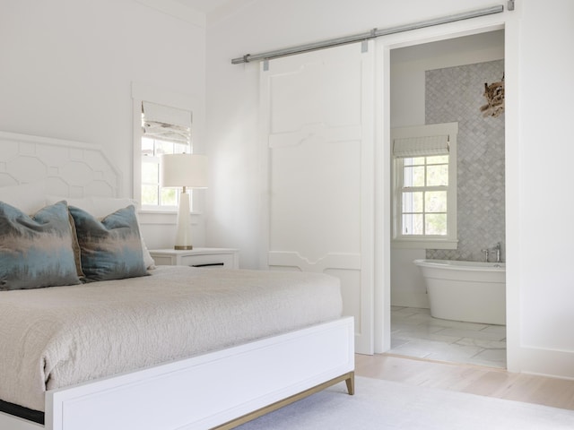 44 Tidepool Ln, Watersound, FL 32461 - bedroom featuring a barn door, multiple windows, and connected bathroom