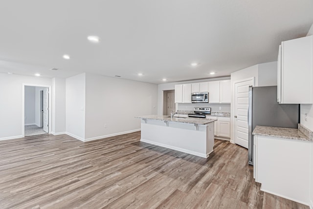 205 Laurel Hill St, Crestview, FL 32539 - kitchen with stainless steel appliances, recessed lighting, light wood-type flooring, white cabinets, and a kitchen island with sink