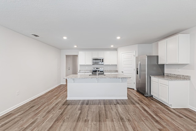 205 Laurel Hill St, Crestview, FL 32539 - kitchen with appliances with stainless steel finishes, light wood finished floors, white cabinetry, recessed lighting, and an island with sink