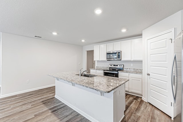 205 Laurel Hill St, Crestview, FL 32539 - kitchen with appliances with stainless steel finishes, a sink, light wood-type flooring, a center island with sink, and white cabinets