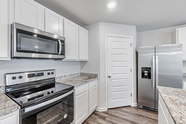 205 Laurel Hill St, Crestview, FL 32539 - kitchen with stainless steel appliances, wood finished floors, white cabinets, light stone countertops, and a textured ceiling