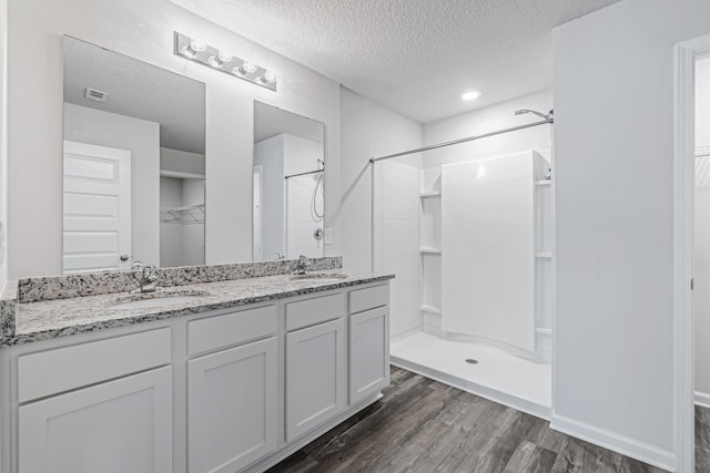 205 Laurel Hill St, Crestview, FL 32539 - full bathroom with a textured ceiling, a stall shower, wood finished floors, a spacious closet, and double vanity