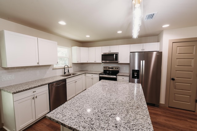 4620 Eagle Way, Crestview, FL 32539 - kitchen with appliances with stainless steel finishes, a center island, white cabinetry, light stone countertops, and tasteful backsplash