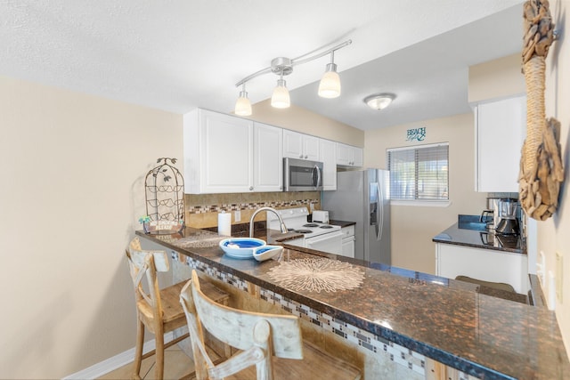 21514 Front Beach Rd, Panama City Beach, FL 32413 - kitchen featuring appliances with stainless steel finishes, backsplash, white cabinets, a peninsula, and dark stone counters