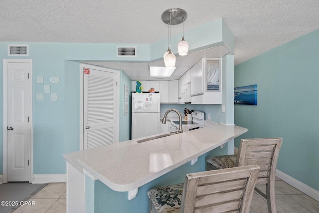 17155 Front Beach Rd Unit W405, Panama City Beach, FL 32413 - kitchen with white appliances, a peninsula, light tile patterned flooring, a sink, and a kitchen breakfast bar