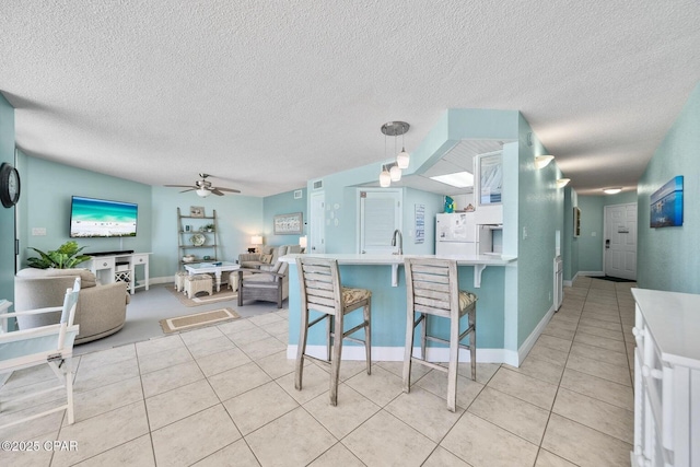 17155 Front Beach Rd Unit W405, Panama City Beach, FL 32413 - kitchen with ceiling fan, light tile patterned floors, a peninsula, a textured ceiling, and a kitchen breakfast bar